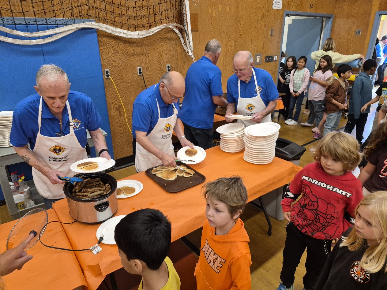 Knights serving pancakes and sausages to a line of students