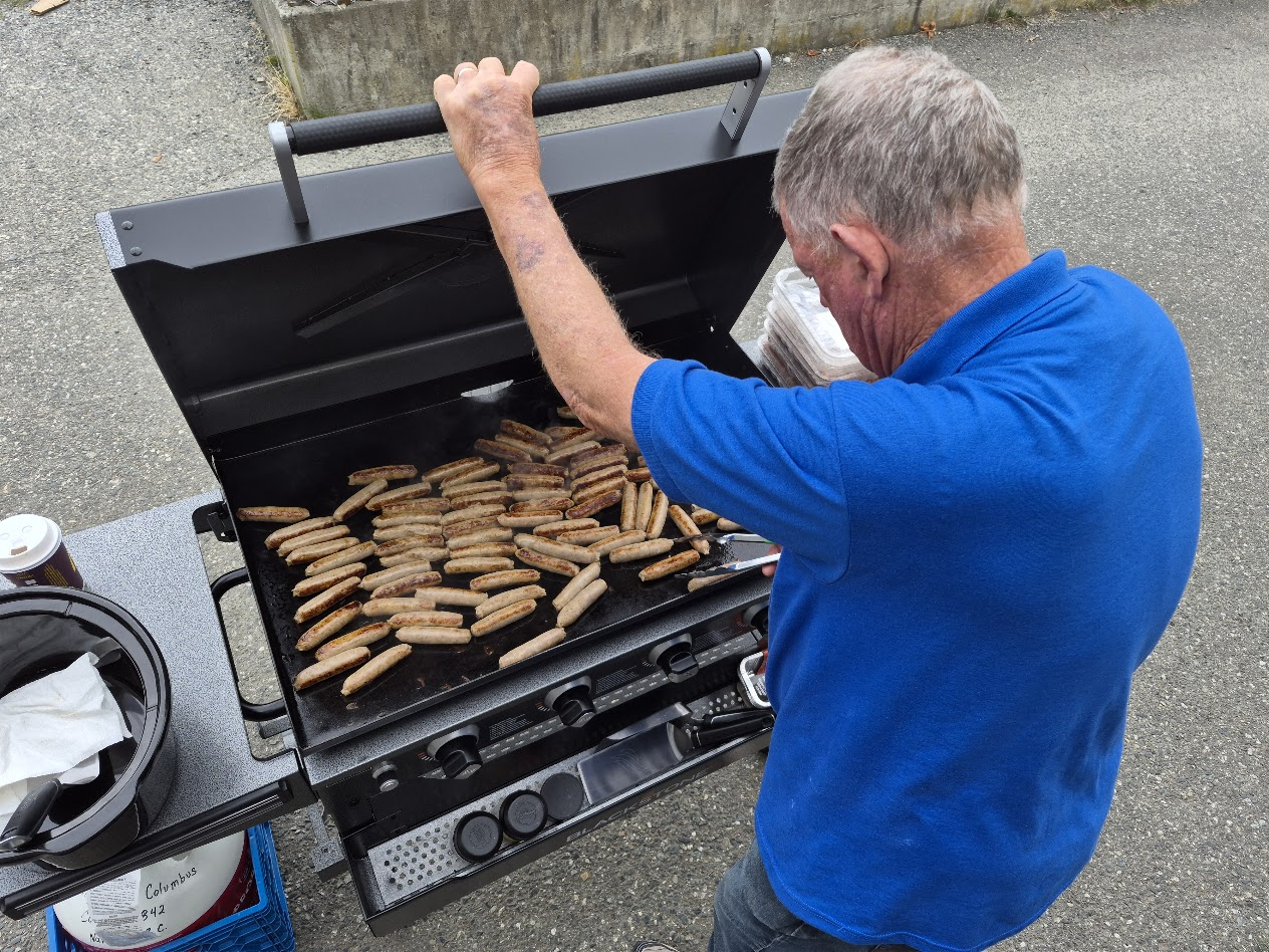 Grilling sausages outdoors for the Rock City School breakfast